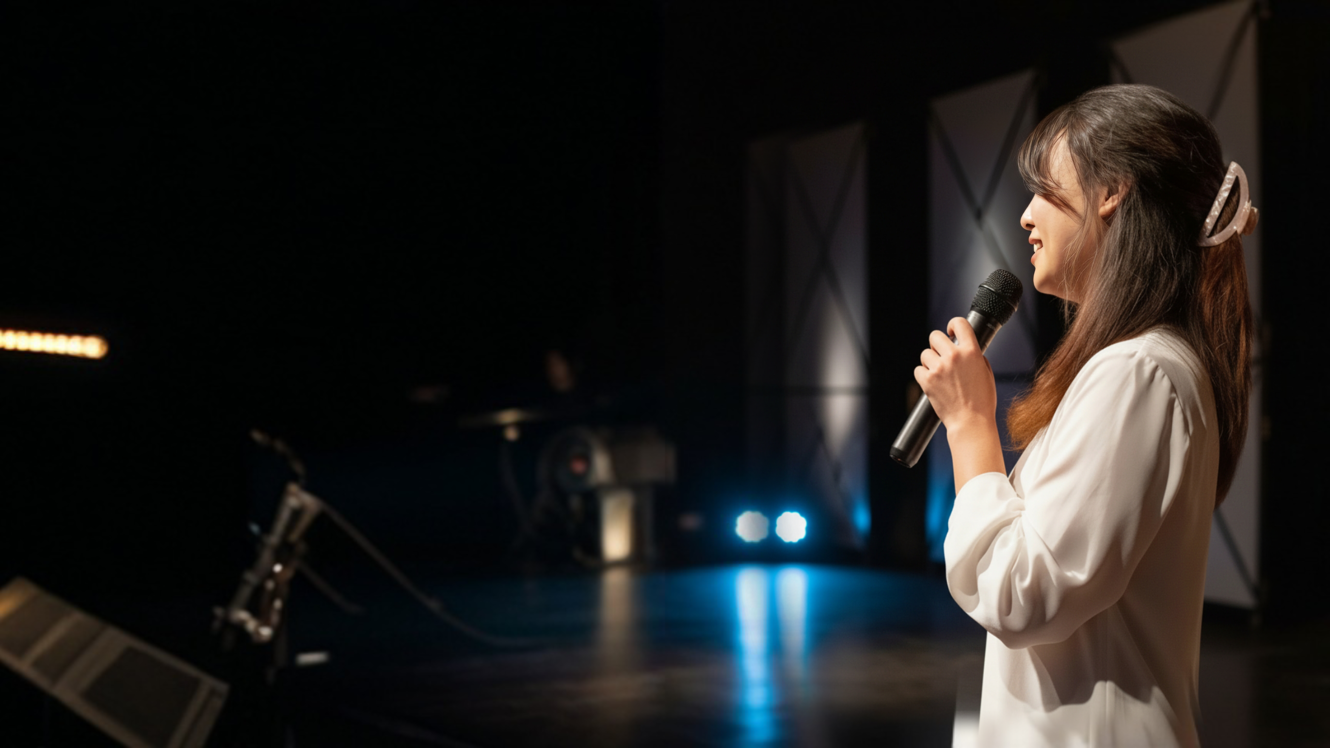 Christi on stage with microphone, spotlight